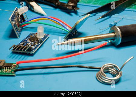 Nahaufnahme eines Arbeitsplatzes mit Lötkolben, Schaltplänen und Drähten. Reparatur der Elektronik. Stockfoto
