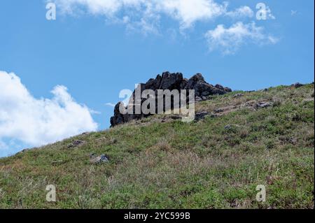 Die Felsformation steht hoch auf einem grasbewachsenen Hügel unter einem hellblauen Himmel in Vereda da Ponta de São Lourenco Stockfoto