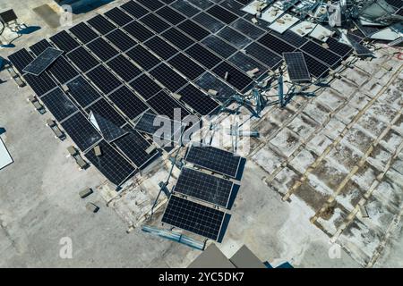 Draufsicht der durch den Hurrikan Ian zerstörten Photovoltaik-Solarpaneele, die auf dem Dach des Industriebaues zur Erzeugung von ökologischem Strom montiert sind. Konse Stockfoto
