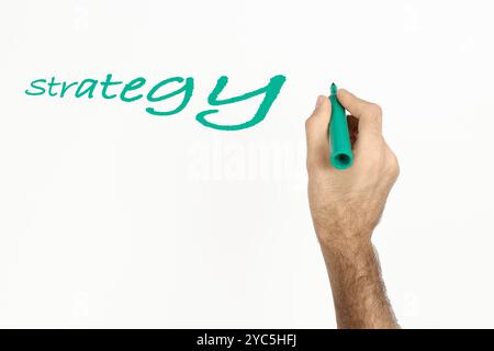 Ein Mann schreibt "Strategie" auf Whiteboard mit grünem Marker. Leerzeichen für Text. Stockfoto