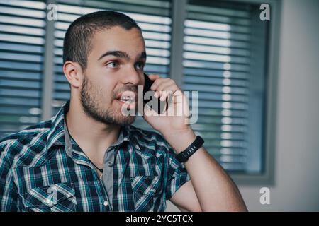 Junge Büroangestellte schaut in einem modernen Büro am Telefon verärgert aus und zeigt Stress und Besorgnis. Das Bild zeigt die Herausforderungen, die sich aus der Balance zwischen Arbeit und e ergeben Stockfoto