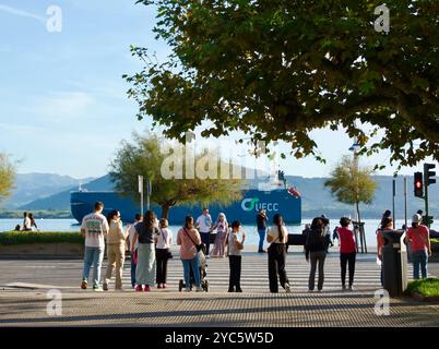 Menschen, die an der Ampel auf die Straße warten, während das Autosun-Frachtschiff den Hafen in der Bucht von Santander Cantabria Spanien verlässt Stockfoto