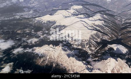 Die Weite und Pracht der schneebedeckten Alpen aus der Perspektive großer Höhen. Zerklüftete Berggipfel erstrecken sich über die Landschaft, bedeckt mit A Stockfoto