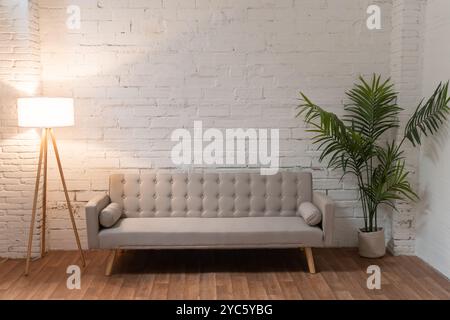 Sofa über weißer Backsteinwand in leerem Wohnzimmer mit Kopierraum Stockfoto