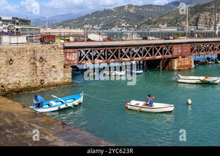 Ruderboote im kleinen Touristenhafen in der Bucht der Märchen, mit dem Pier und der Küste im Hintergrund im Frühling, Sestri Levante, Ligurien Stockfoto