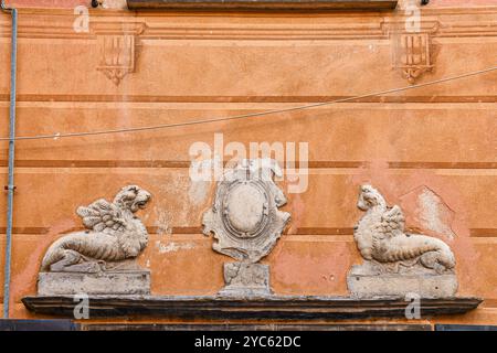 Ein Basrelieffries aus Schieferstein, das ein Paar geflügelter Löwen oder Chimären darstellt, an der Fassade eines alten Palastes, Sestri Levante, Genua, Ligurien Stockfoto