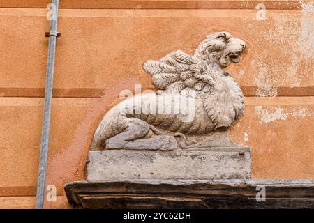 Detail einer Übertür aus Schieferstein, die einen geflügelten Löwen oder eine Chimera darstellt, an der Fassade eines alten Palastes, Sestri Levante, Genua, Ligurien, Italien Stockfoto