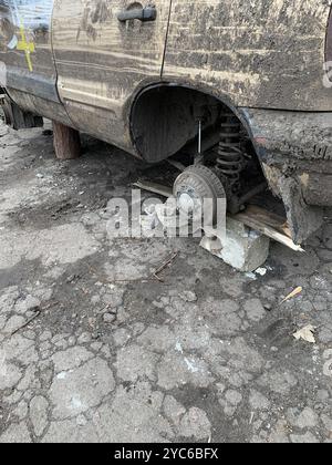 Dreckiger, schäbiger Pkw ohne Räder auf Ziegelstein. Stockfoto