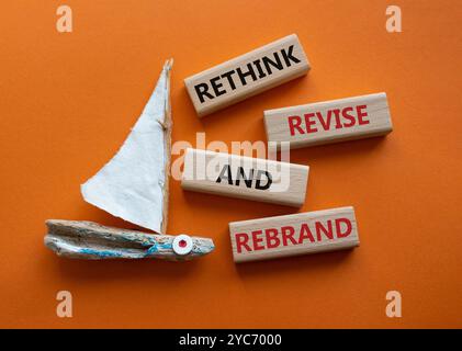 Überdenken Sie das Symbol „Überarbeiten“ und „Rebranding“. Holzblöcke mit Wörtern überdenken und neu gestalten. Schöner oranger Hintergrund mit Boot. Unternehmen und Umdenken Stockfoto