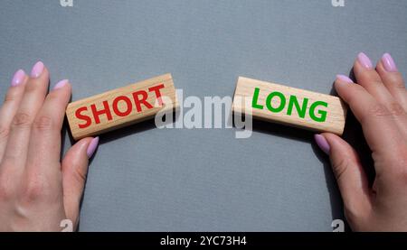 Symbol kurz vs lang. Konzeptwort kurz vs lang auf Holzblöcken. Geschäftsmann Hand. Schöner grauer Hintergrund. Business und kurz- vs Langkonzept. Co Stockfoto