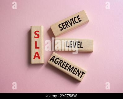 SLA - Service Level Agreement. Holzblöcke mit Wort SLA. Schöner rosafarbener Hintergrund. Business- und Service Level Agreement-Konzept. Kopierbereich. Stockfoto