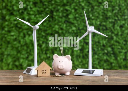 Windturbinenmodelle mit Hausfigur und Schweinebank auf Tisch im Freien. Konzept der grünen Energie Stockfoto