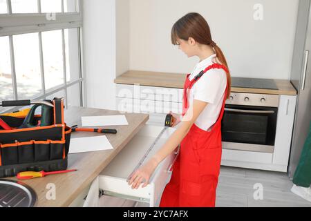 Weibliche Arbeiterin, die die Schublade in der Küche misst Stockfoto