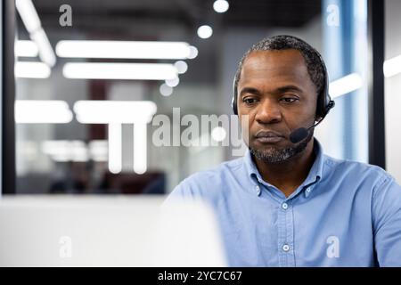 Reifer Geschäftsmann mit Headset in moderner Büroumgebung. Konzentriert sich auf die Arbeit, engagiert in virtuellen Meetings, spiegelt Professionalität und Konzentration wider. Cor Stockfoto