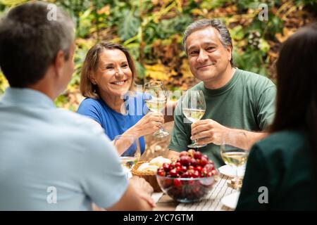 Freunde genießen ein fröhliches Treffen mit Wein in einer lebhaften Umgebung im Freien Stockfoto