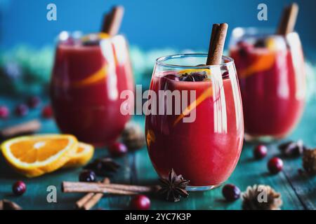 Drei Gläser weihnachtlicher Glühwein mit Orangenscheiben, Zimtrinde, Anisstern und Tannenzweigen auf rustikalem farbenfrohen Tisch. Selektiv Stockfoto