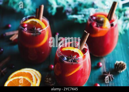 Drei Gläser weihnachtlicher Glühwein mit Orangenscheiben, Zimtrinde, Anisstern und Tannenzweigen auf rustikalem farbenfrohen Tisch. Selektiv Stockfoto