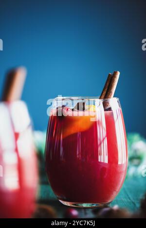 Zwei Gläser weihnachtlicher Glühwein mit Orangenscheiben, Zimtrinde, Anisstern und Tannenzweigen auf rustikalem farbenfrohen Tisch. Selektiv fo Stockfoto