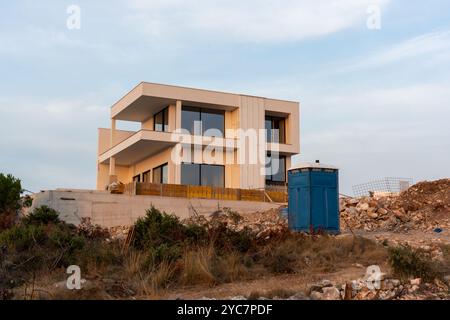 Modernes zweistöckiges Haus im Bau in einer ländlichen Gegend während Sonnenuntergang. Stockfoto