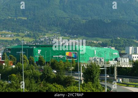 Innsbruck, Österreich - 13. Juni 2023: Unter einem klaren blauen Himmel besticht ein lebhaftes Sportgelände mit seinem markanten grünen Äußeren, umgeben von atemberaubendem Ambiente Stockfoto