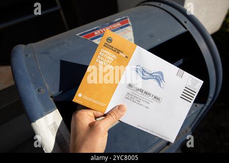 Fullerton, Kalifornien, USA - 20. Oktober 2024: Eine kaukasische Hand lässt eine Wahl per Briefwahl in einem Briefkasten für die Präsidentschaftswahlen für 2024 fallen. Stockfoto