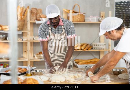 Zwei Bäcker kneten Teig und Rollen ihn aus Stockfoto