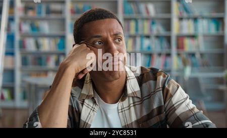 Gelangweilt unglücklicher Afroamerikaner Bibliotheksschüler lernen Studie negative Bildungsuniversität unzufrieden männlich unzufrieden Mann Langeweile müde faul Stockfoto