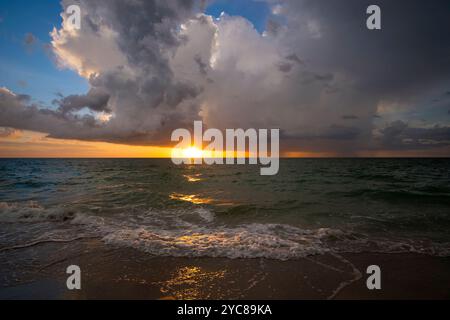 Ozeanlandschaft mit Gewitterwolken über rauen abendlichen Meerwasserwellen, die am Sandstrand zerquetschen. Wunderschöne Meereslandschaft bei Sonnenuntergang. Stockfoto