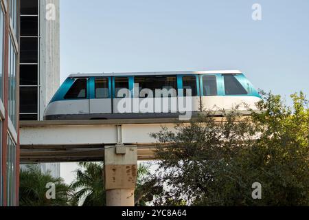 Stadtverkehr im Stadtteil Miami Brickell in Florida, USA. Metrorail-Stadtzug auf hoher Eisenbahn über Straßenverkehr zwischen Himmel Stockfoto