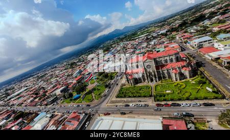 Wunderschöner FPV-Blick auf die zweihundertjährige Flagge von Costa Rica im Coronado Park mit der gotischen Kirche. Costa Rica Stockfoto