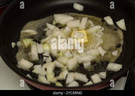 Fein gehackte Zwiebeln werden in Butter in Nahaufnahme gebraten Stockfoto