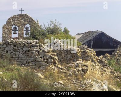 Glockengiebel zwischen zerbröckelnden Häusern in einem halb verlassenen Dorf, Foncebadon, Kastilien und Leon, Spanien, Europa Stockfoto