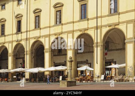 Cafés und Restaurants bereiten das Mittagessen unter der gelben Fassade und den eleganten Bögen von Loggia del Vasari, Arezzo, Toskana, Italien, 24. September 2011 vor. Eu Stockfoto