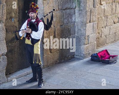 Camino-Pilger werden von einem galizischen Dudelsackspieler begrüßt, der unter einem Steinbogen (Arco de Palacio) zum Obradoiro-Platz in Santiago de Busse fährt Stockfoto