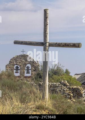 Kreuze und Glocken zwischen zerbröckelnden Häusern in einem halb verlassenen Dorf, Foncebadon, Kastilien und Leon, Spanien, Europa Stockfoto