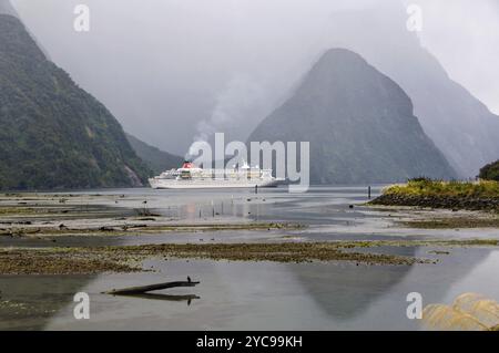 Kreuzfahrtschiff am Abend an einem bewölkten Tag in den majestätischen Milford Sound auf der Südinsel Neuseelands Stockfoto