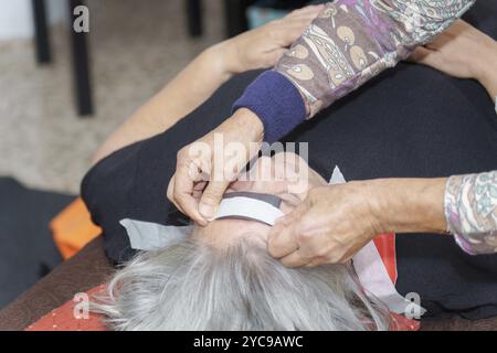 Ein Therapeut legt während einer Biomagnetismus-Sitzung einen Magneten auf den Kopf eines Patienten Stockfoto