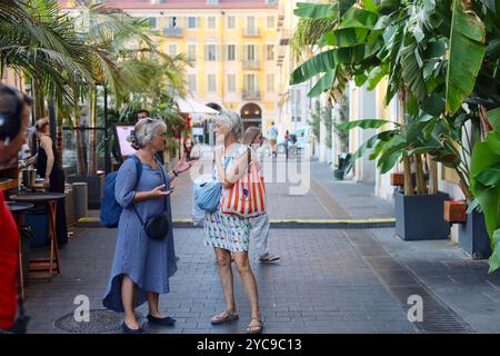 Nizza, Frankreich - 9. August 2024: Zwei aktive ältere Damen unterhalten sich vor einem Restaurant auf der Piazza Garibaldi Stockfoto