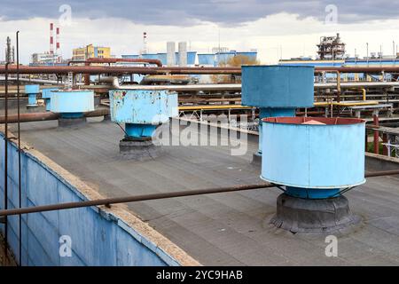 Lüfteranlage für die Lüfteranlage des industriellen Produktionsgebäudes einer großen petrochemischen Werkstatt. Schornsteinschächte mit Kapuze und Kanäle in Reihe auf dem Dach Stockfoto