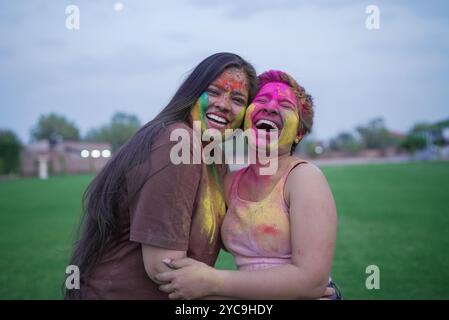 Zwei fröhliche junge indische Freundinnen, bedeckt mit buntem Pulver oder gulal, feiern das holi Festival der Farben. Kultur indiens. Lachende Mädchen Stockfoto