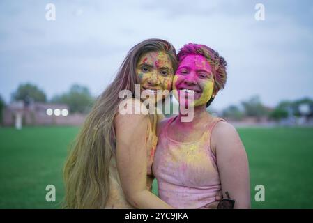 Zwei fröhliche junge indische Freundinnen, bedeckt mit buntem Pulver oder gulal, feiern das holi Festival der Farben. Kultur indiens. Lachende Mädchen Stockfoto