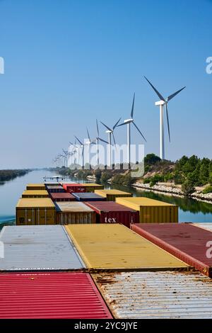 Rhone-Schifffahrtskanal im Hafen von Fos-sur-Mer (Südostfrankreich): Das Guadiana-Containerschiff auf dem Kanal und Reihen von Windturbinen, Wind FAR Stockfoto