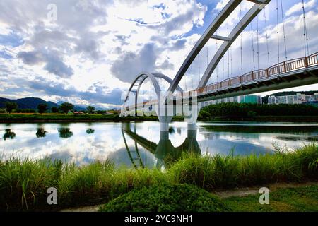 Ulsan, Südkorea - 9. Juli 2019: Die Simnidaebat Bridge überspannt anmutig den ruhigen Taehwa River, mit einem dramatischen Himmel und Reflexen in der Ruhe Stockfoto