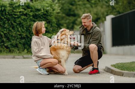 Golden Retriever gibt Paw dem Besitzer, der mit seiner Tochter Einen Sommerspaziergang gemacht hat Stockfoto