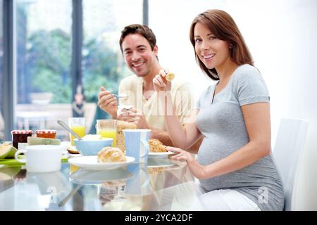 Schwangere Frau, Essen oder Porträt des Paares mit Frühstück für gesunde Ernährung oder Ernährung zu Hause. Menschen, Wellness oder Essen mit Schwangerschaft genießen Stockfoto