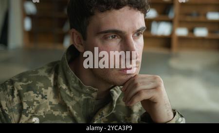 Beweglicher verschwommener Schuss besorgter kaukasischer männlicher Offizier Tarnuniform Mann mit Behinderung Militärsoldat verloren in Gedanken Kerl im Rollstuhl Stockfoto