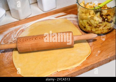 Rollteig für Apfelstrudel. In Scheiben geschnittener Apfel und Rosinen in einer Schüssel auf dem Küchenbrett. Zubereitung süßer Kuchen. Stockfoto