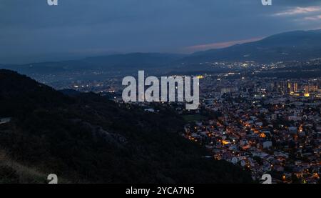 Die Stadt wird bei Dämmerung beleuchtet, von oben gesehen. Die europäische Hauptstadt Nordmazedoniens, Skopje. Stockfoto