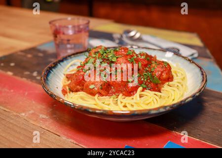Ein schöner Teller mit Spaghetti und Fleischbällchen auf einem hölzernen Hintergrund mit Koriandergarnierung auf der Oberseite Stockfoto