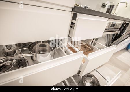 Die Küche verfügt über ordentlich organisierte Töpfe und Utensilien in offenen Schubladen, die ein modernes Design mit einer sauberen Ästhetik hervorheben. Stockfoto